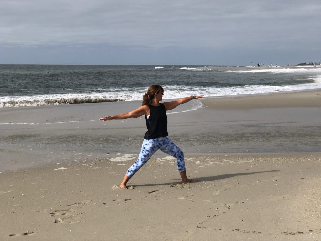 janice on beach doing yoga warrior pose