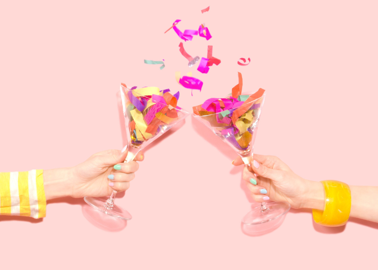 person's hands holding two champagne glasses full of confetti